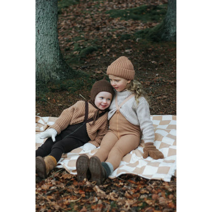 Zwei Kinder auf einer karierten Decke im Herbstlaub mit Wooly Strumpfhosen
