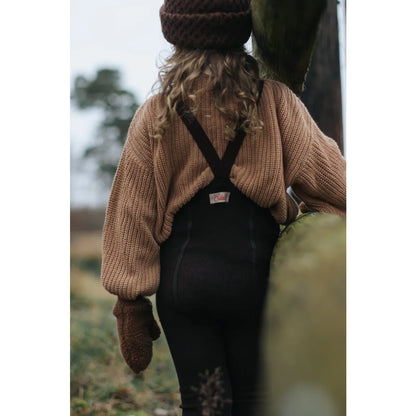 Person mit dickem Strickpullover und dunklem Latzrock in Espressobraun