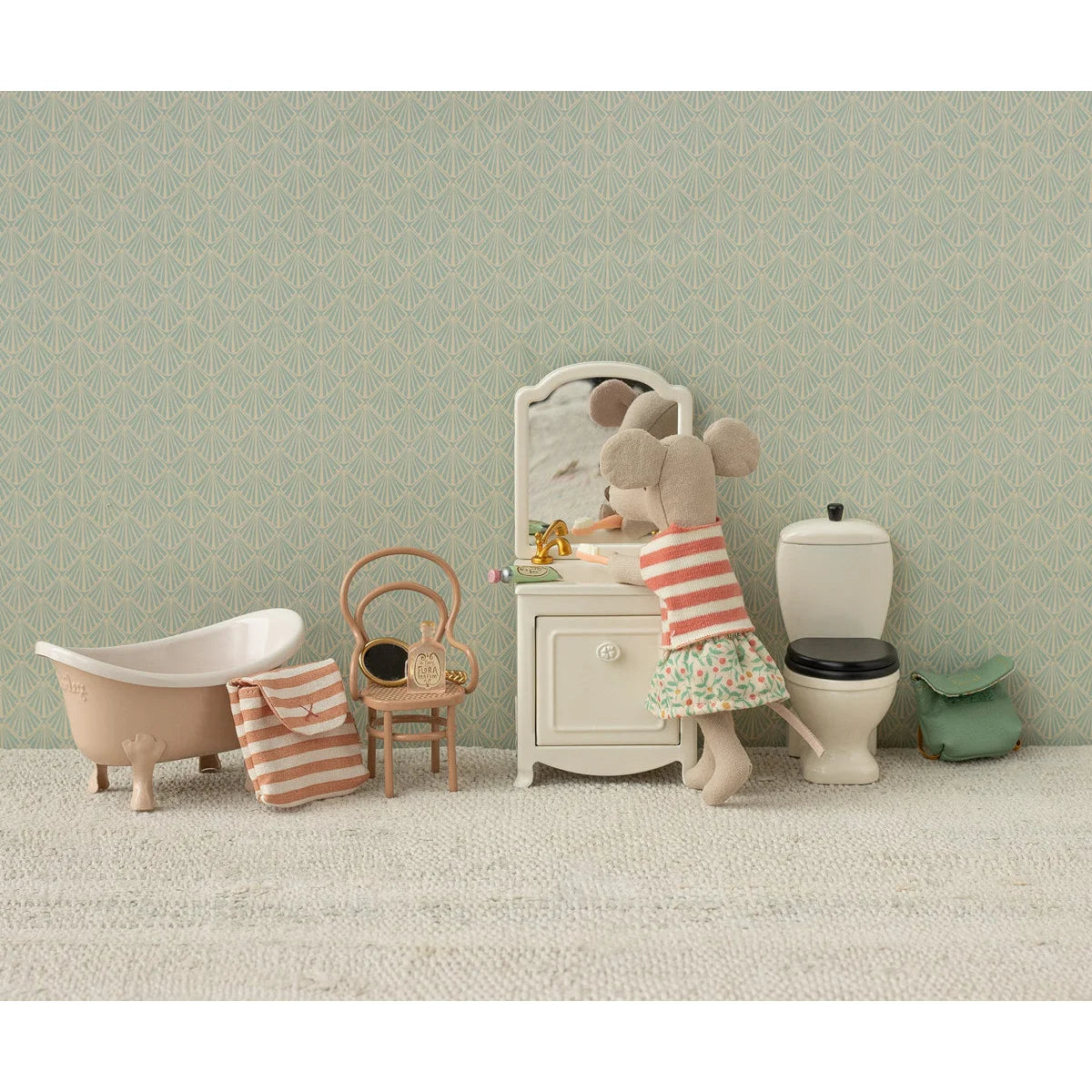 Ein plush maus doll mit rot weiß gestreiftem top und floralem rock vor miniatur schminkspiegel nachhaltige babykleidung
