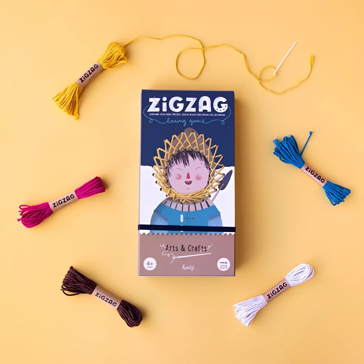 Zig Zag Spielbox mit bunter Stickgarn und Nadel drumherum